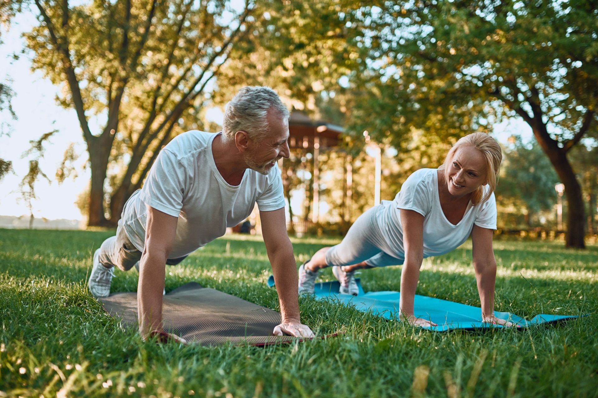 A couple doing yoga in a park.