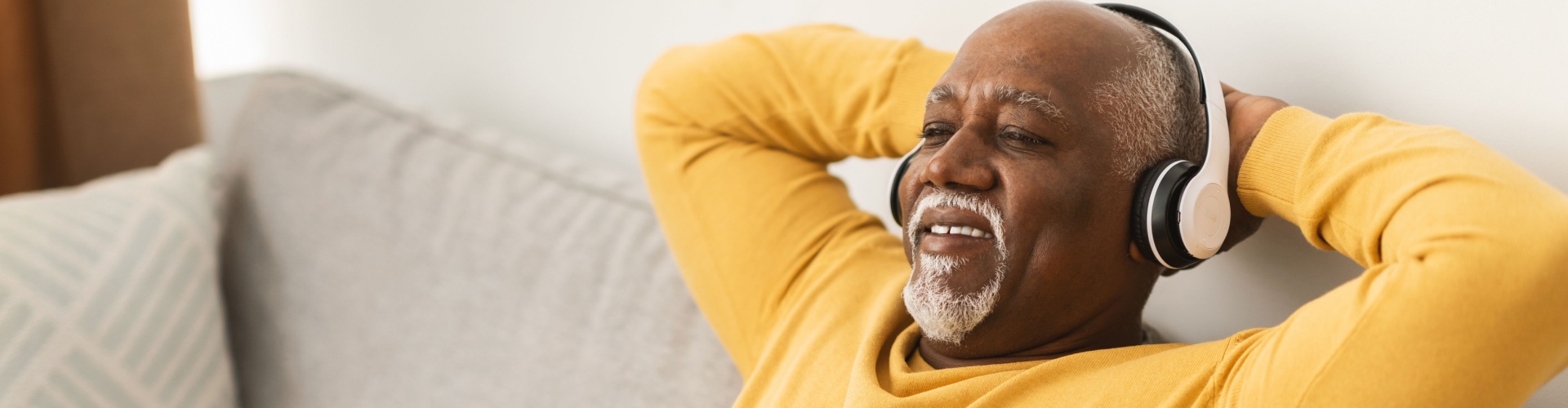 A man relaxing on a sofa with his hands behind his head.