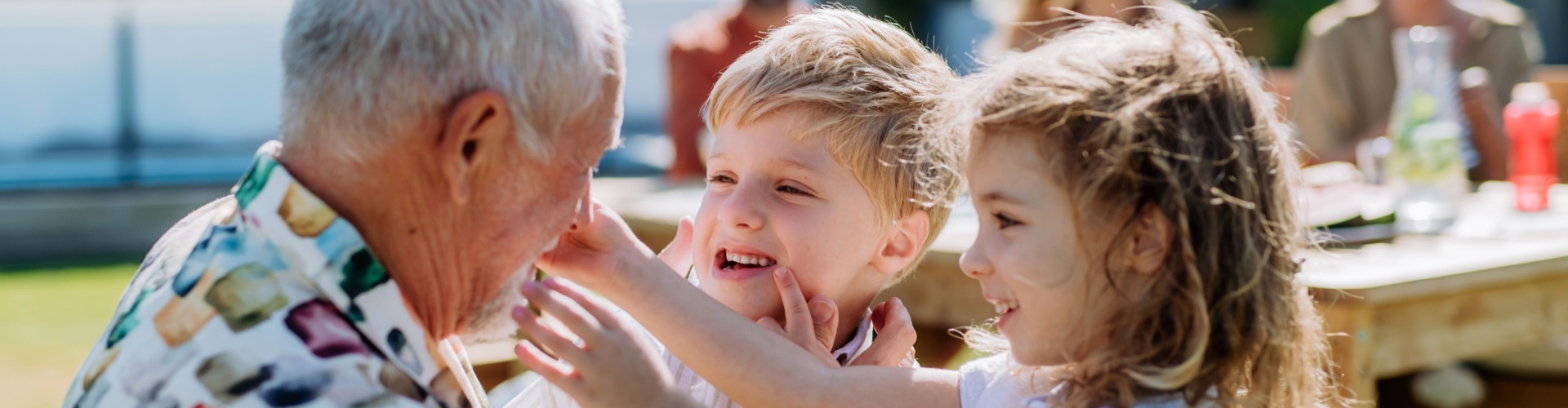 A grandfather playing with his grandchildren outdoors