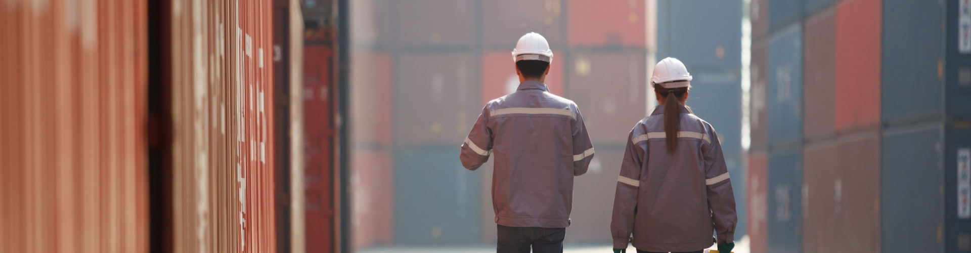Two workers walking between shopping containers.