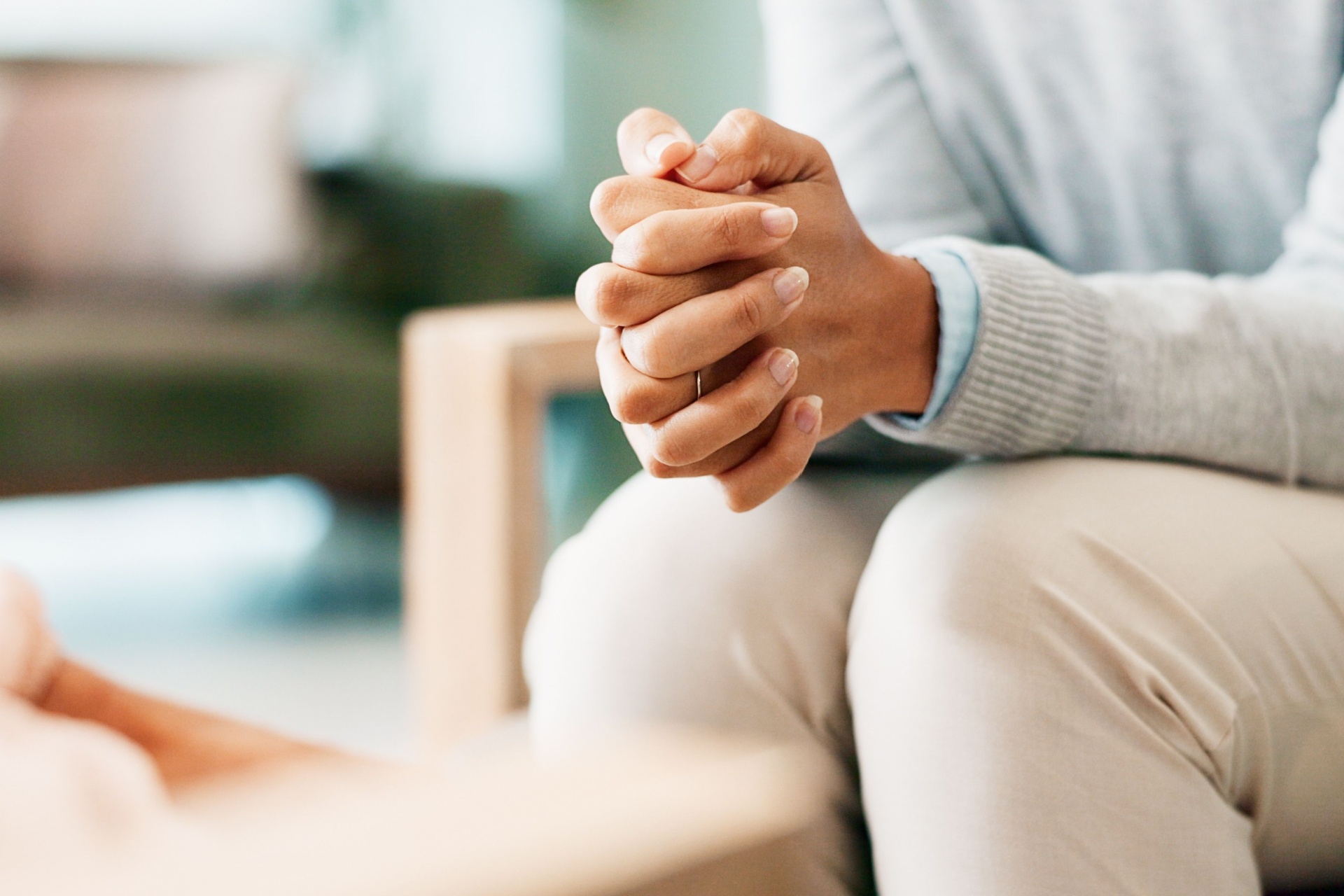 A woman sitting with her hands clasped.