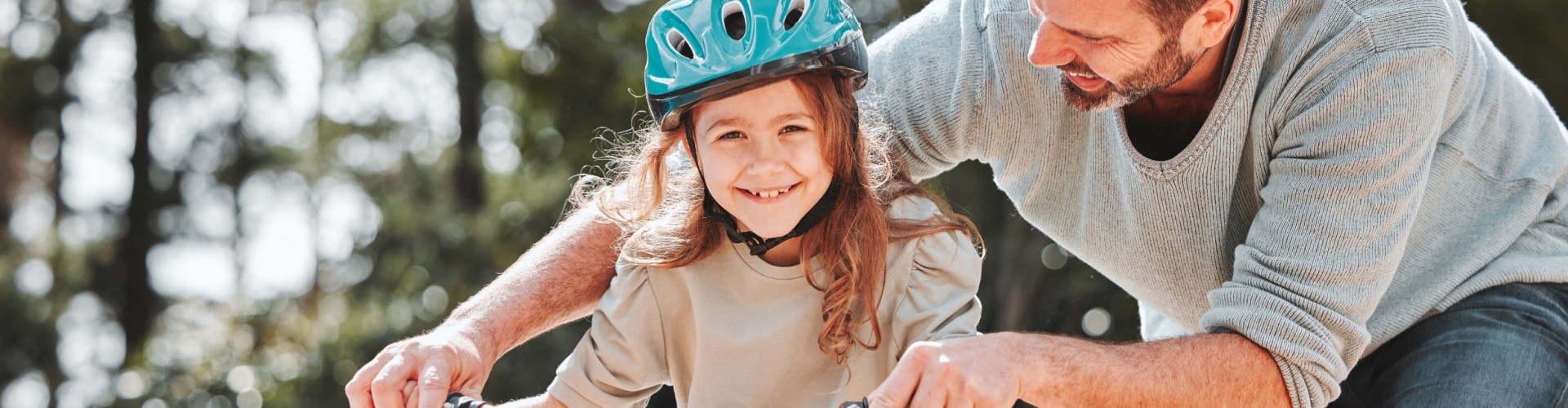 A father teaching his daughter to ride a bike.