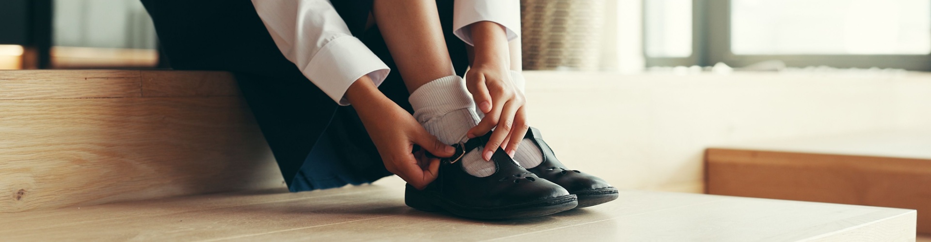 A girl putting on school shoes.