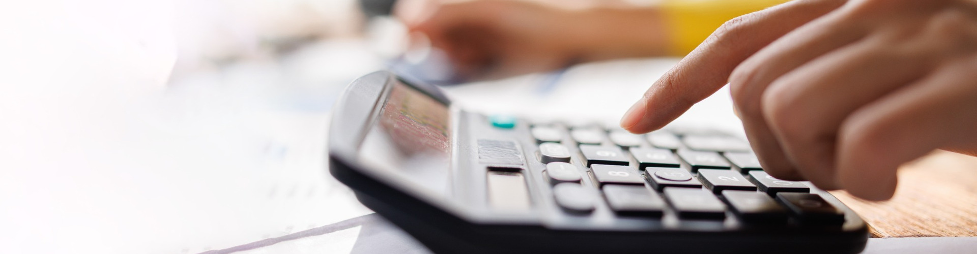 A person using a calculator while reviewing paperwork.