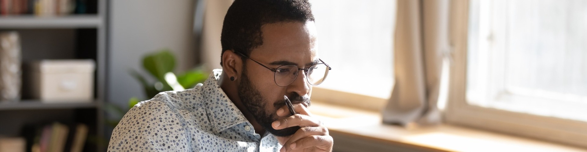 A man looking contemplatively at a desk.
