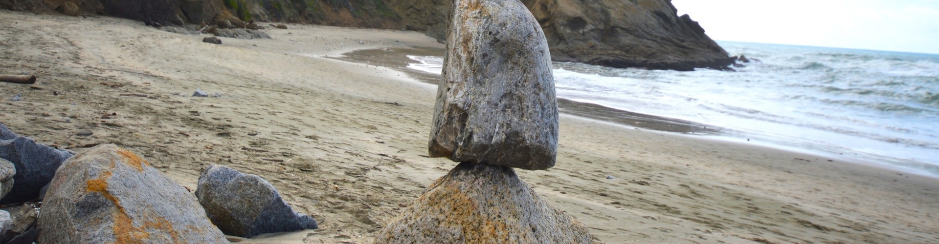 Rocks balancing on log on top of another rock